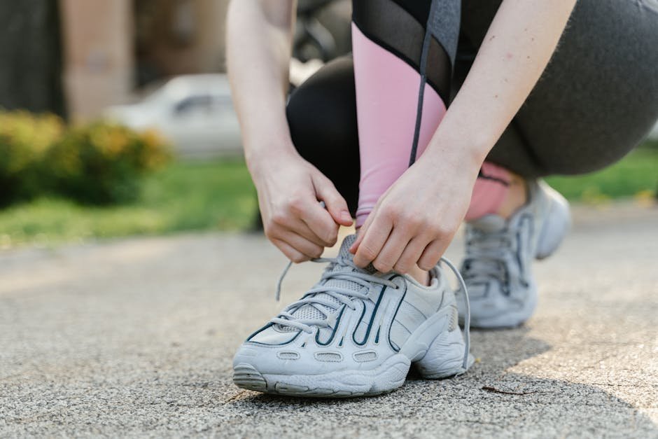 Woman tying her running shoes at dawn on an apartment step, focused and ready to start.
